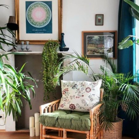 Rattanstuhl mit Grünpflanzen vor Kamin